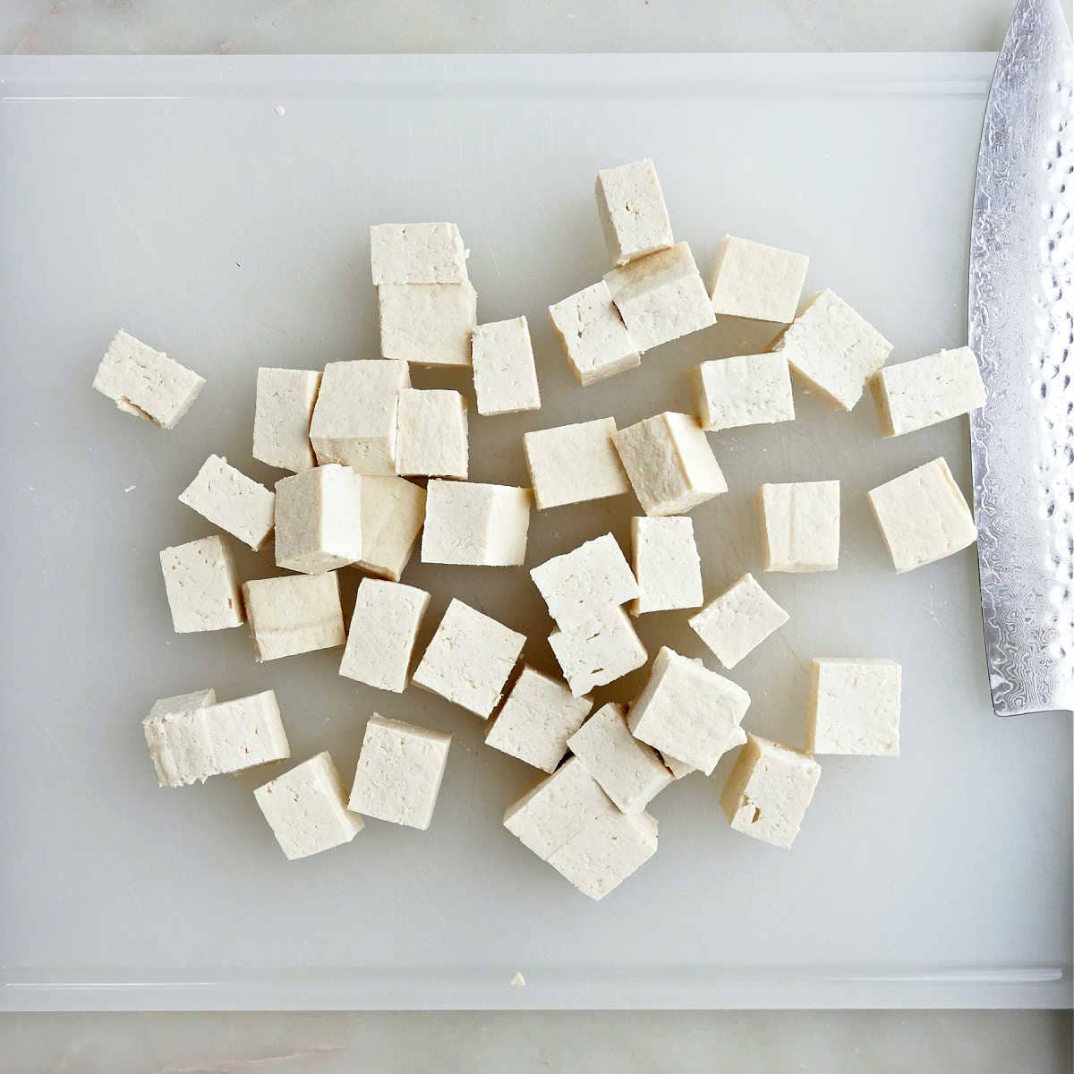 Sliced tofu cut into squares on a baking sheet.