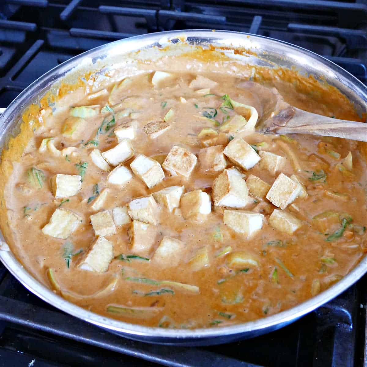 Stirring in the cooked tofu to the coconut milk peanut butter sauce.