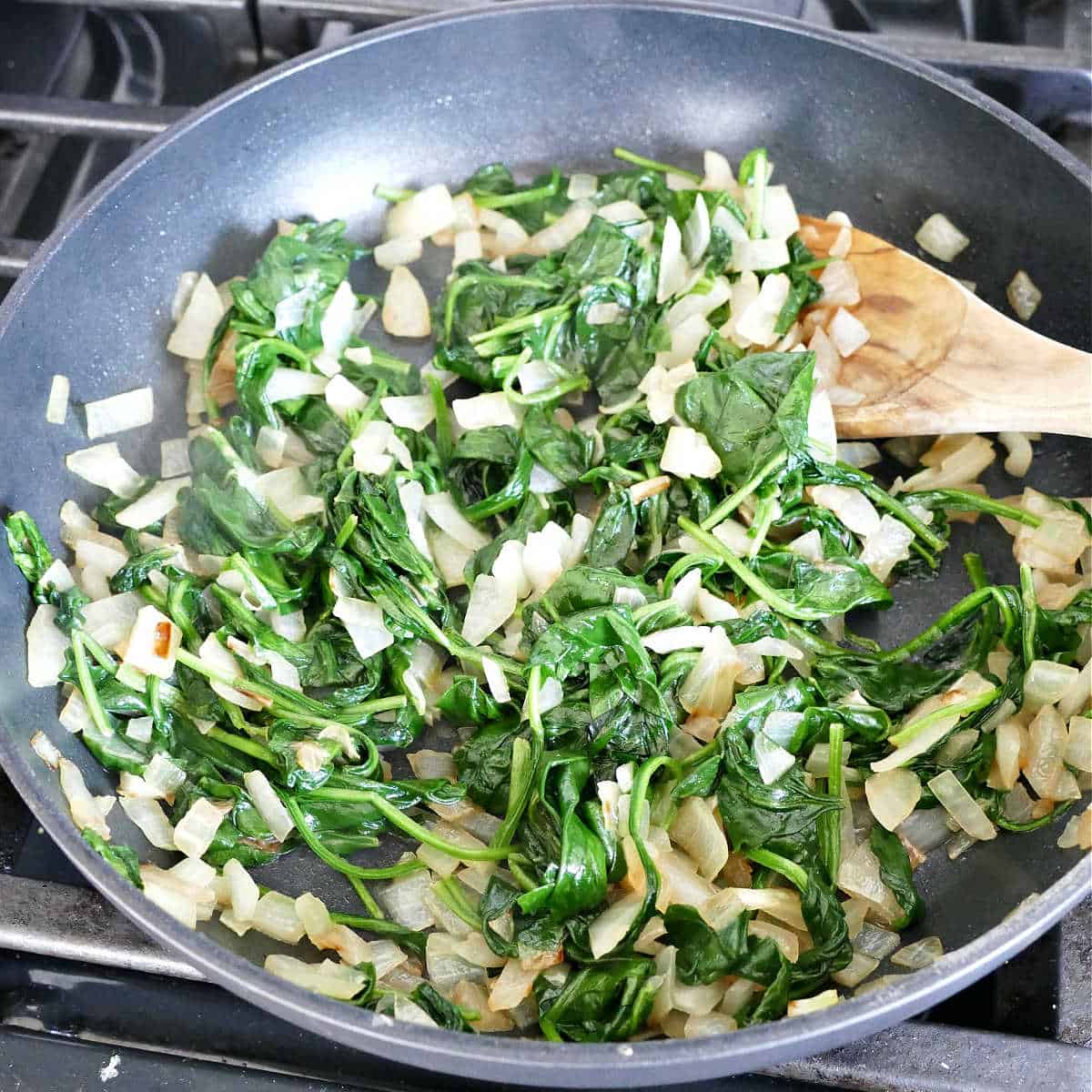 Cooking the spinach and onions in a skillet.