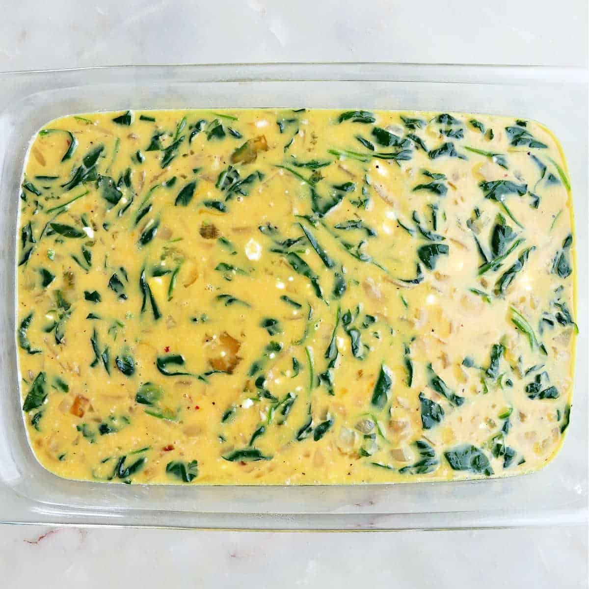 Spinach egg bake in a dish before cooking.