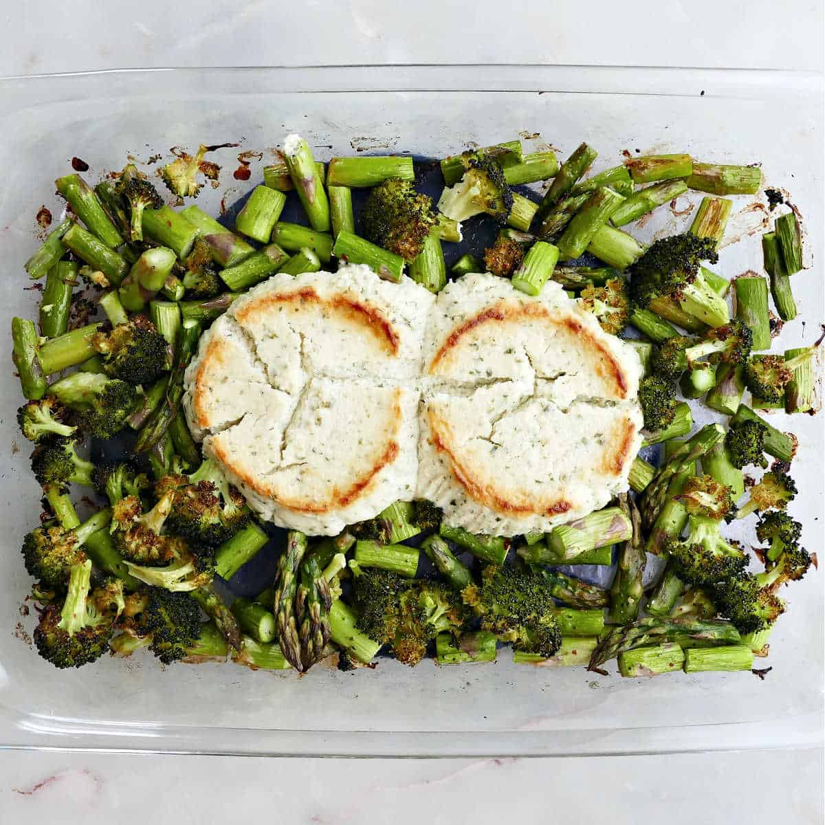 Asparagus and broccoli topped with cheese in a baking dish after baking.