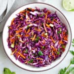 Cabbage carrot slaw in a large serving bowl next to a lime.