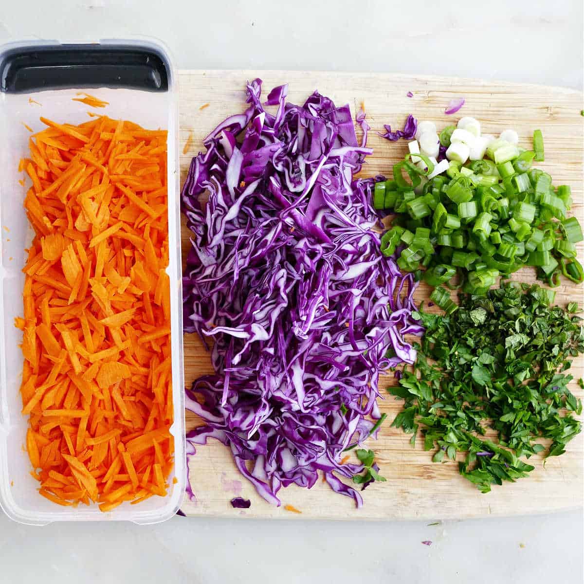 Chopped ingredients for the simple cabbage carrot slaw on a cutting board.