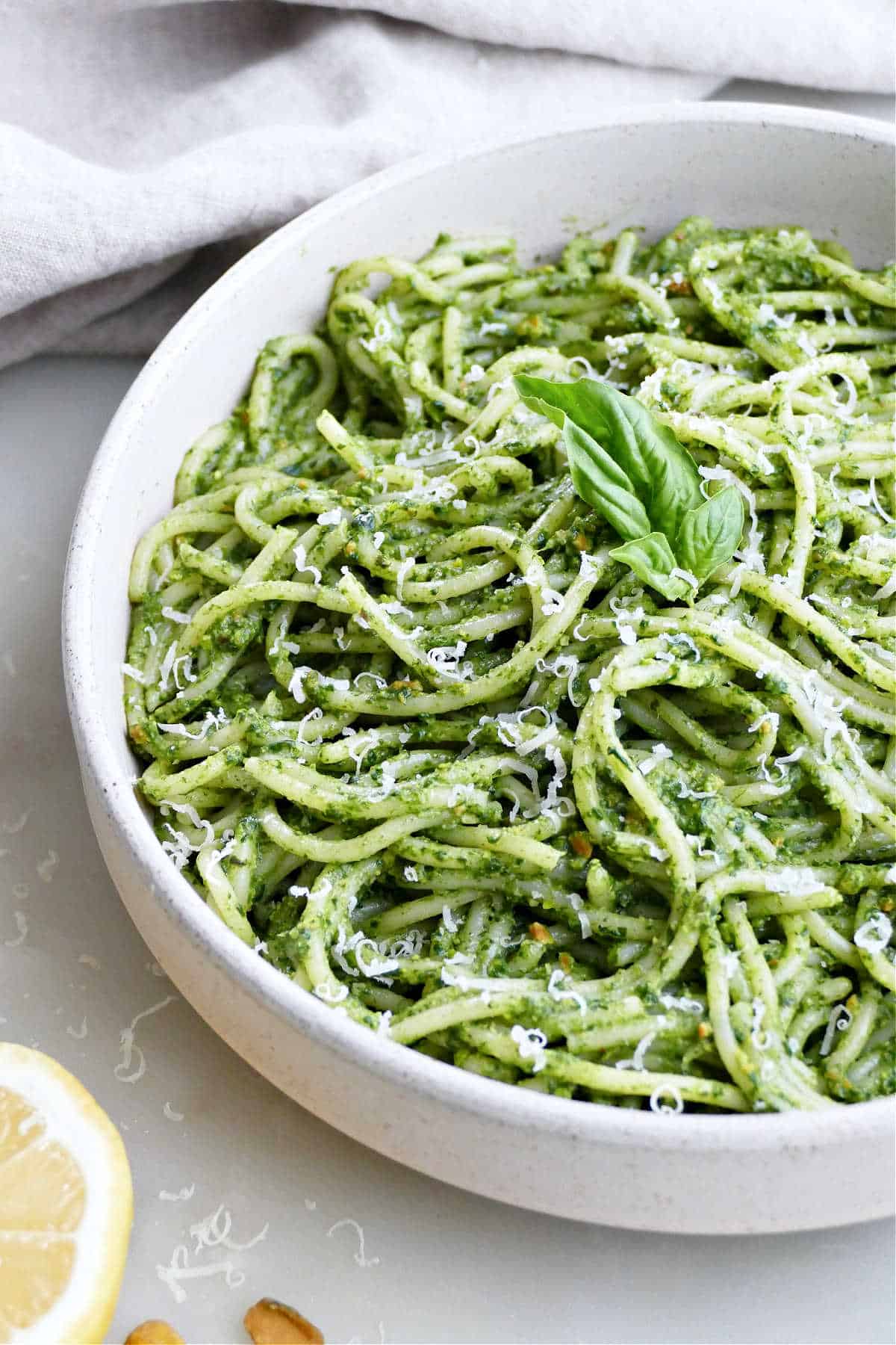 Spinach basil spaghetti in a serving bowl on a counter.