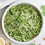 spaghetti coated in green pasta sauce in a serving bowl.