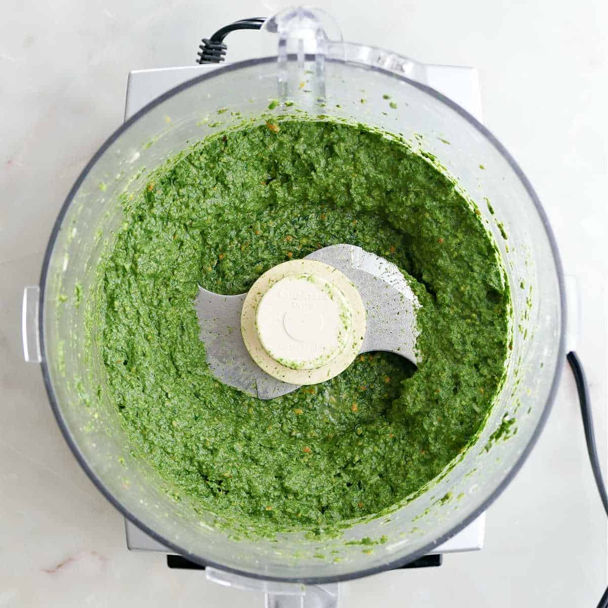 Blended green pasta sauce in a food processor on a counter.