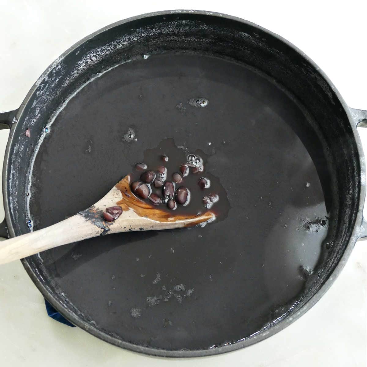 Stirring the black beans in a pot with a wooden spoon.