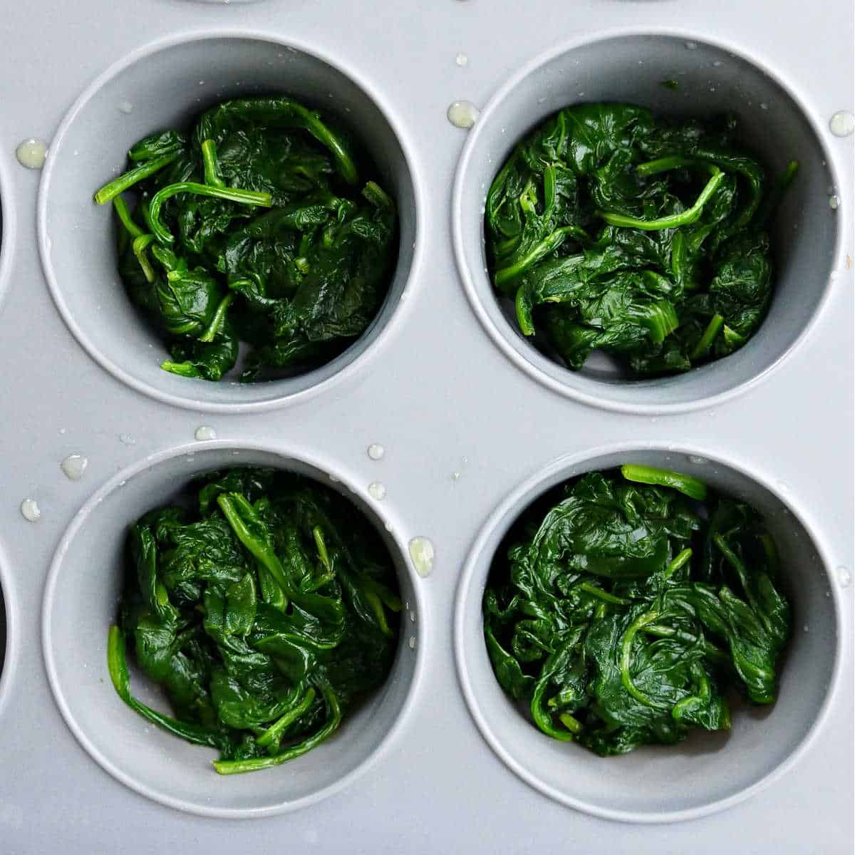 Portioned spinach in a muffin tin to freeze.