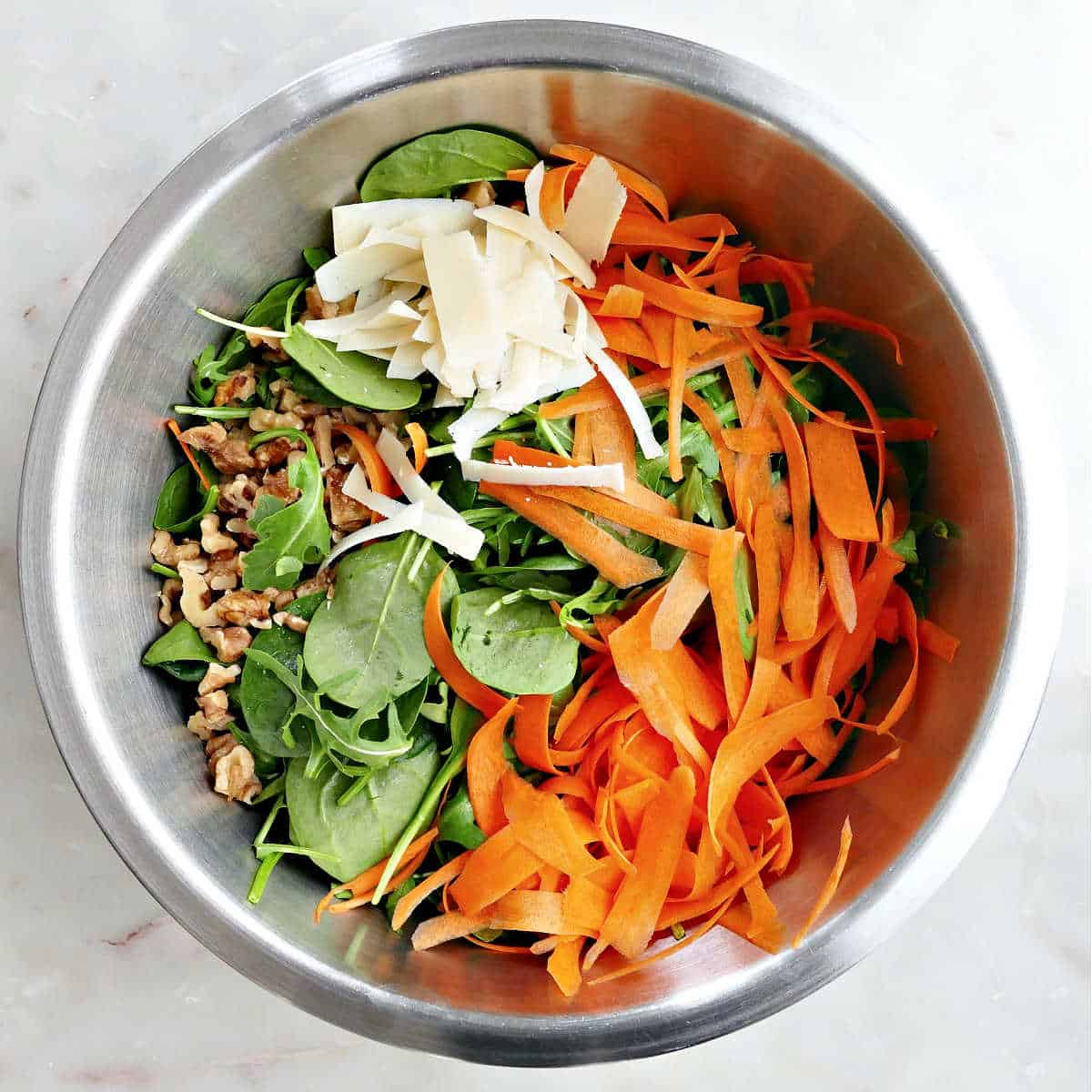 Arugula spinach salad in a mixing bowl before adding the dressing.