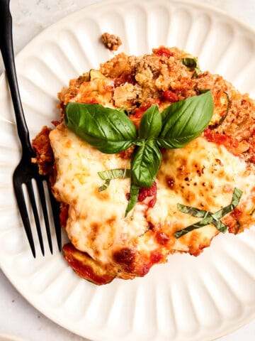 Ground beef, quinoa, and zucchini casserole on a plate with a fork.
