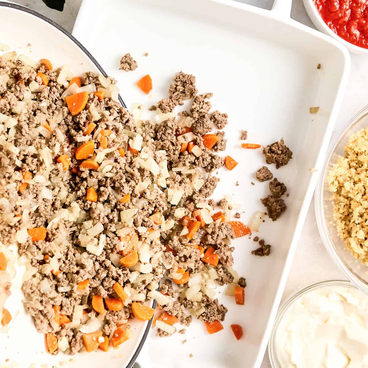 Woman transferring beef, carrot, and onion mixture to a casserole dish.