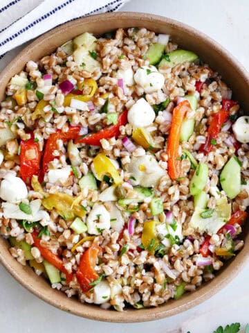 A bowl of Italian farro salad with Mediterranean veggies garnished with parsley.