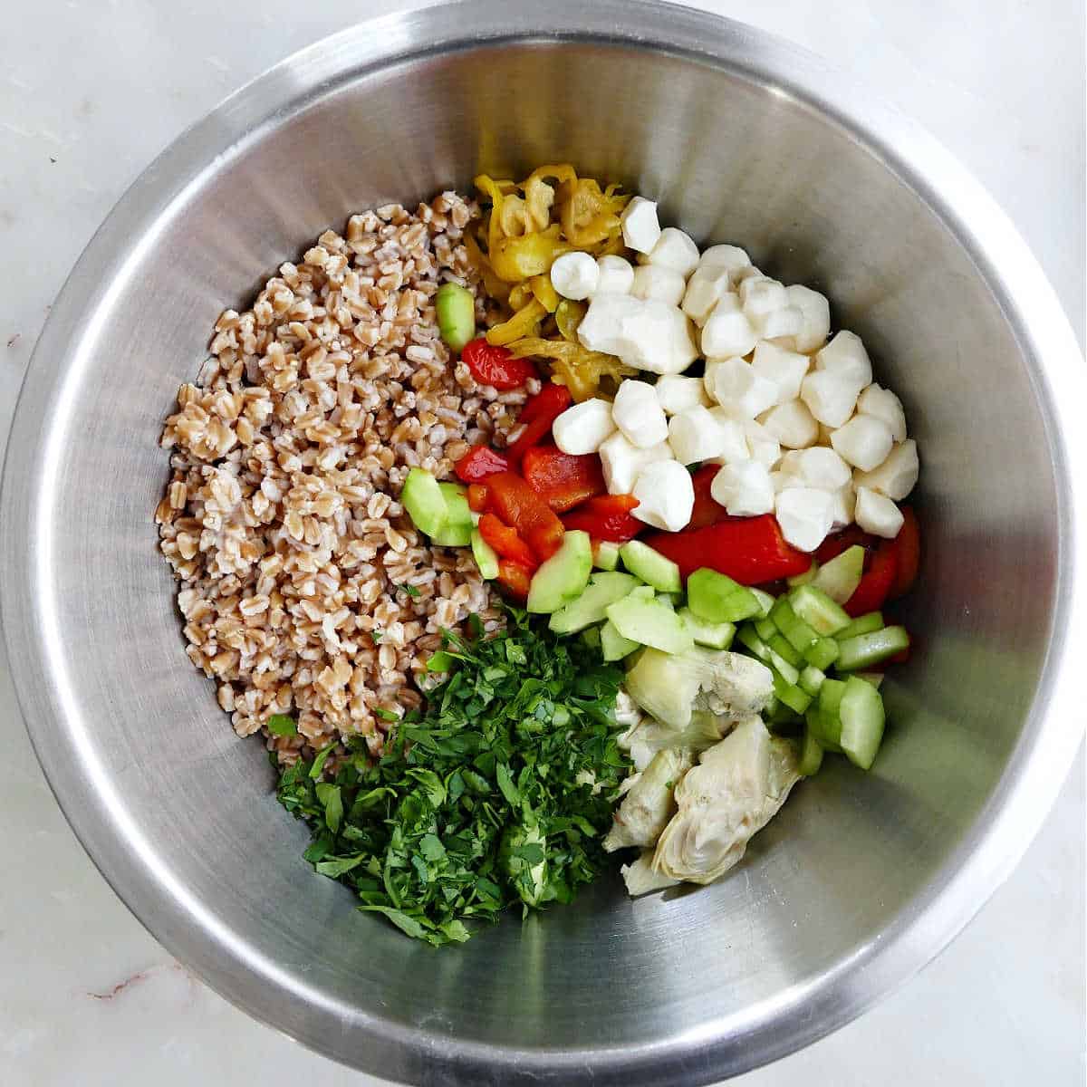 All of the ingredients in a mixing bowl to make Italian farro salad.