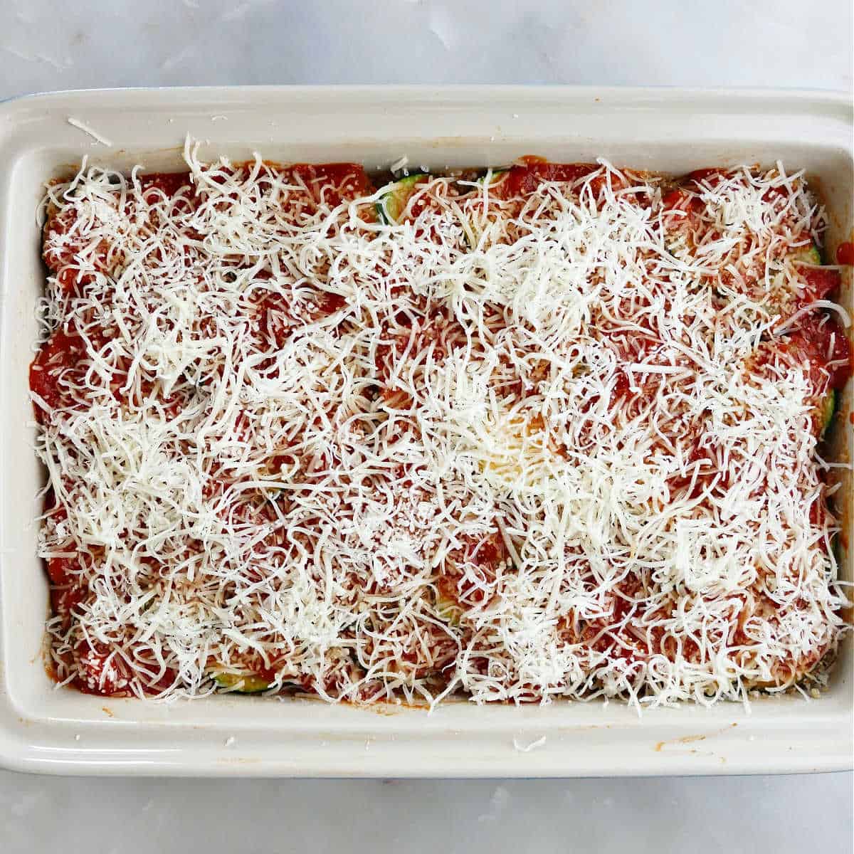 Sprinkled cheese on top of the zucchini ground beef casserole before baking.