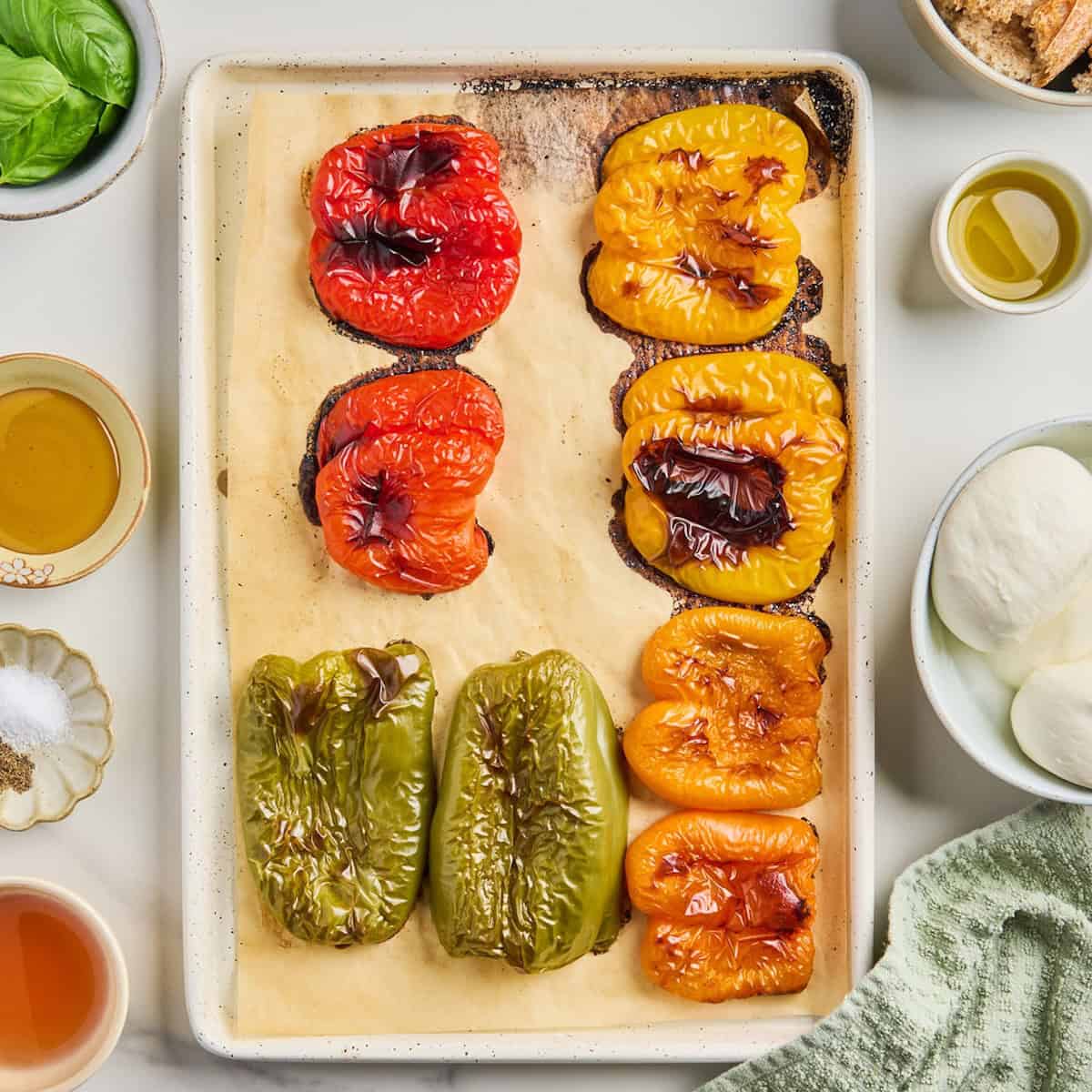 Roasted bell pepper halves on a baking sheet after coming out of the oven.