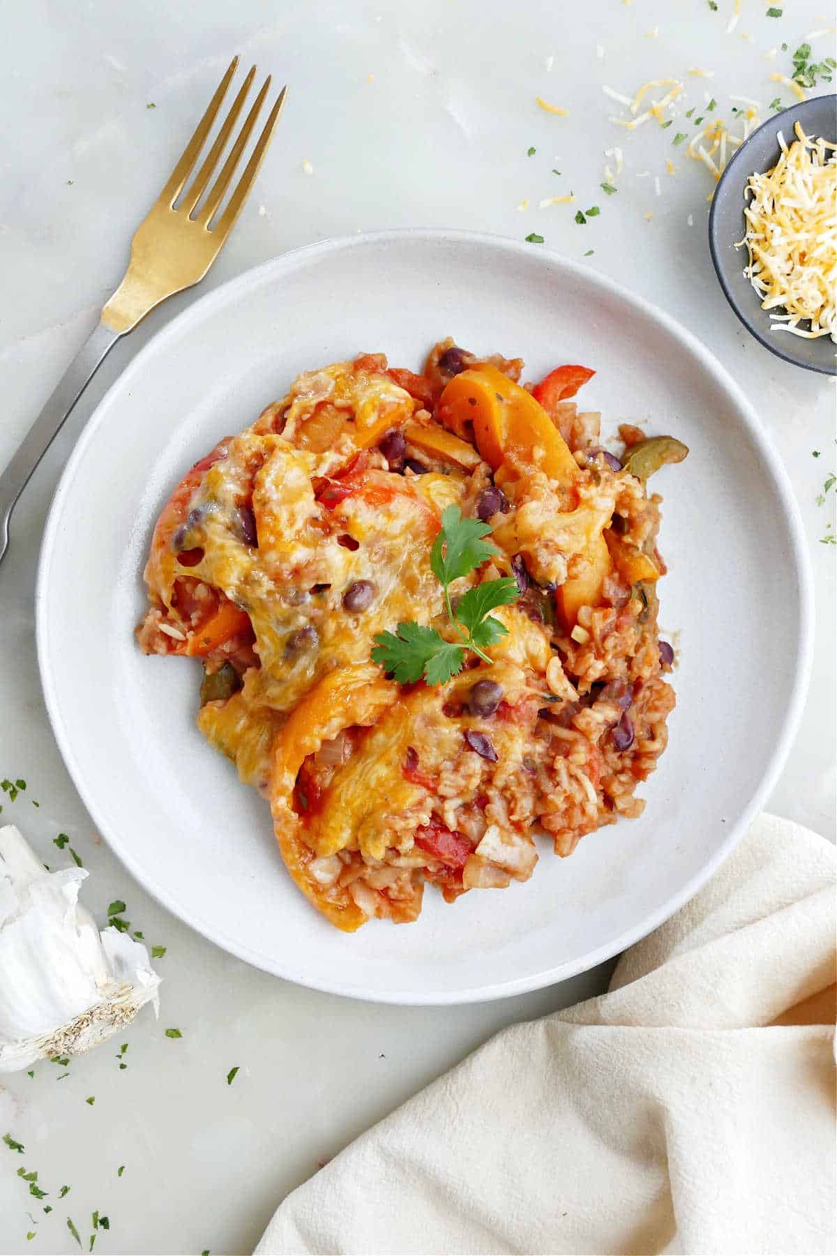 Crockpot stuffed pepper casserole on a white plate next to a fork and cheese.