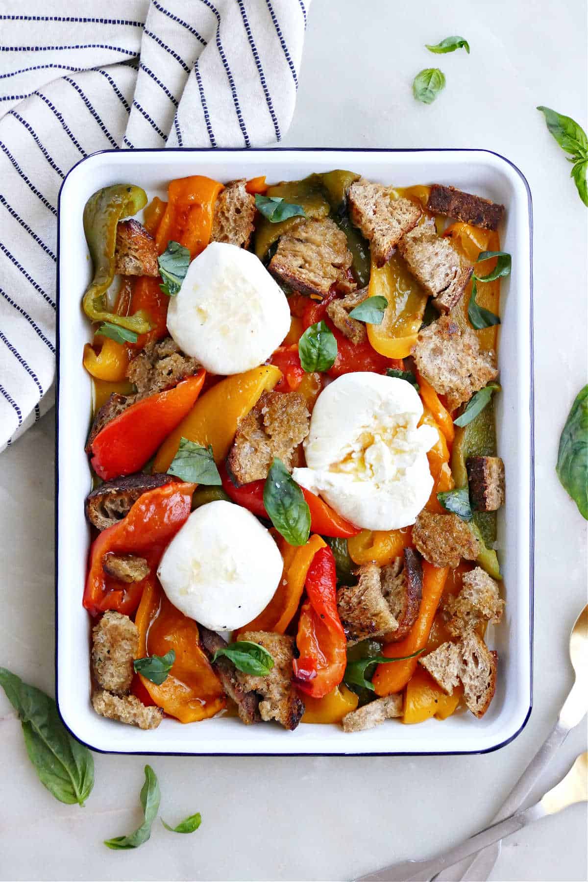 Roasted bell pepper salad on a serving tray next to napkin and utensils.