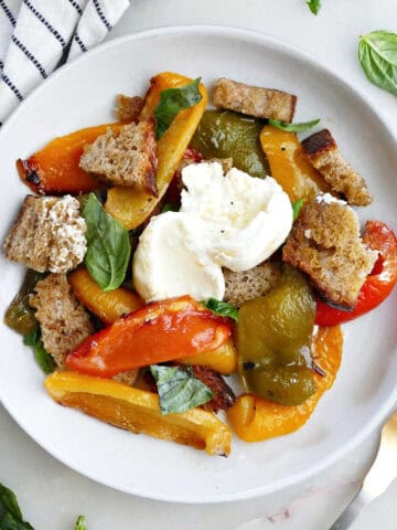 Serving of roasted bell pepper salad on a plate next to a fork and napkin.