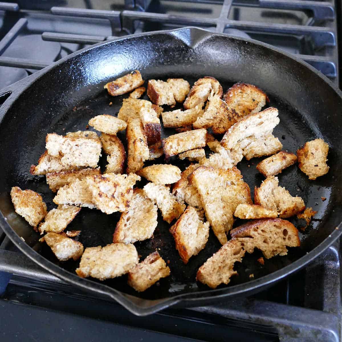 Croutons cooked in a cast iron skillet on a stove.