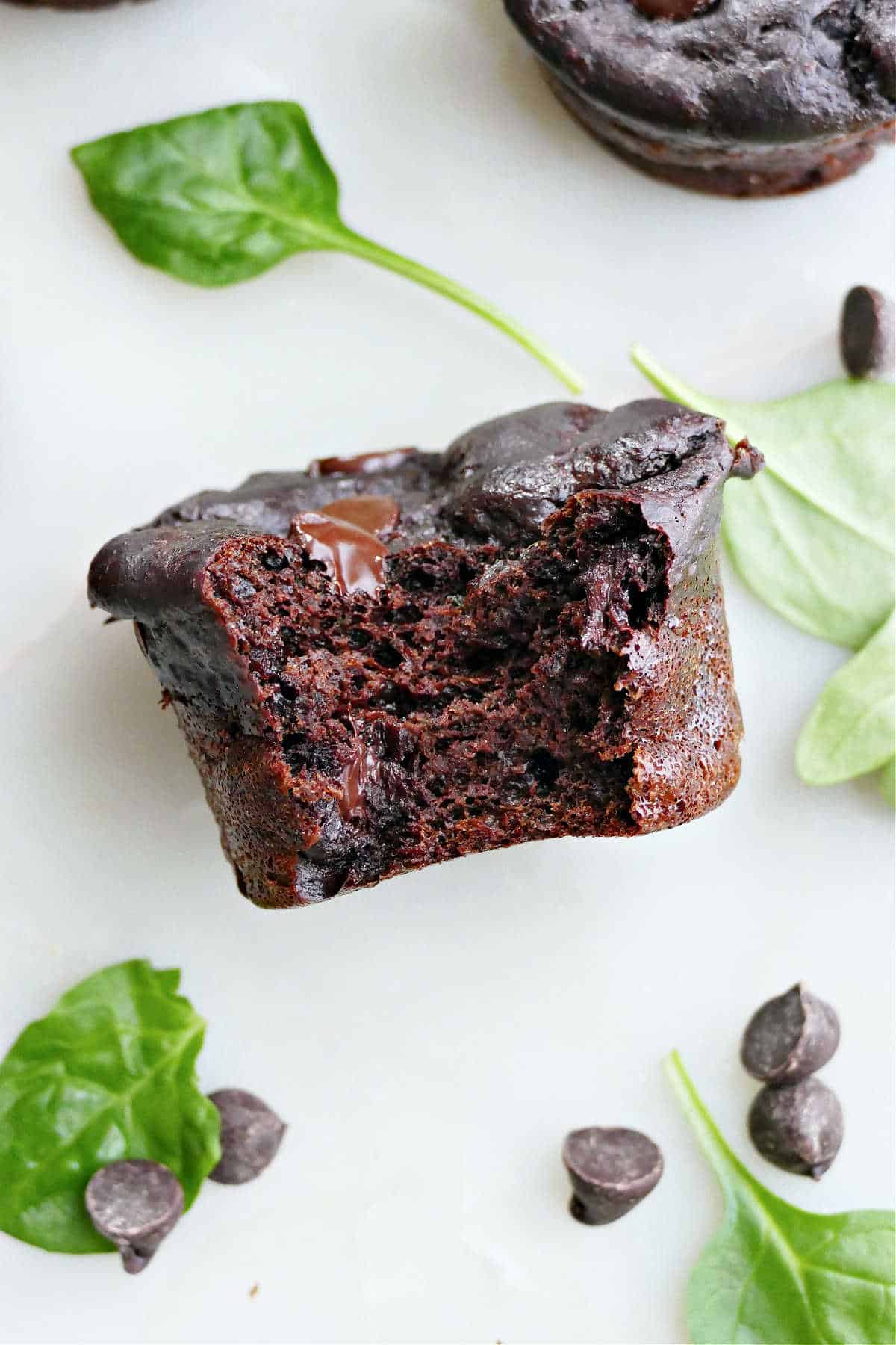 Spinach chocolate muffin with a bite taken out of it on a counter.