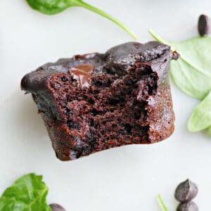 Spinach chocolate muffin with a bite taken out of it on a counter.