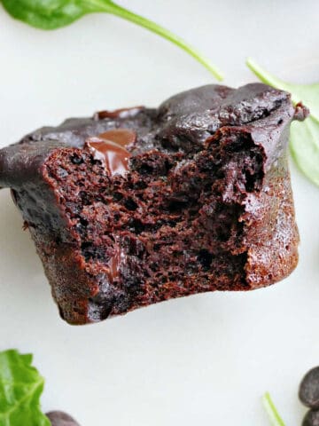 Spinach chocolate muffin with a bite taken out of it on a counter.