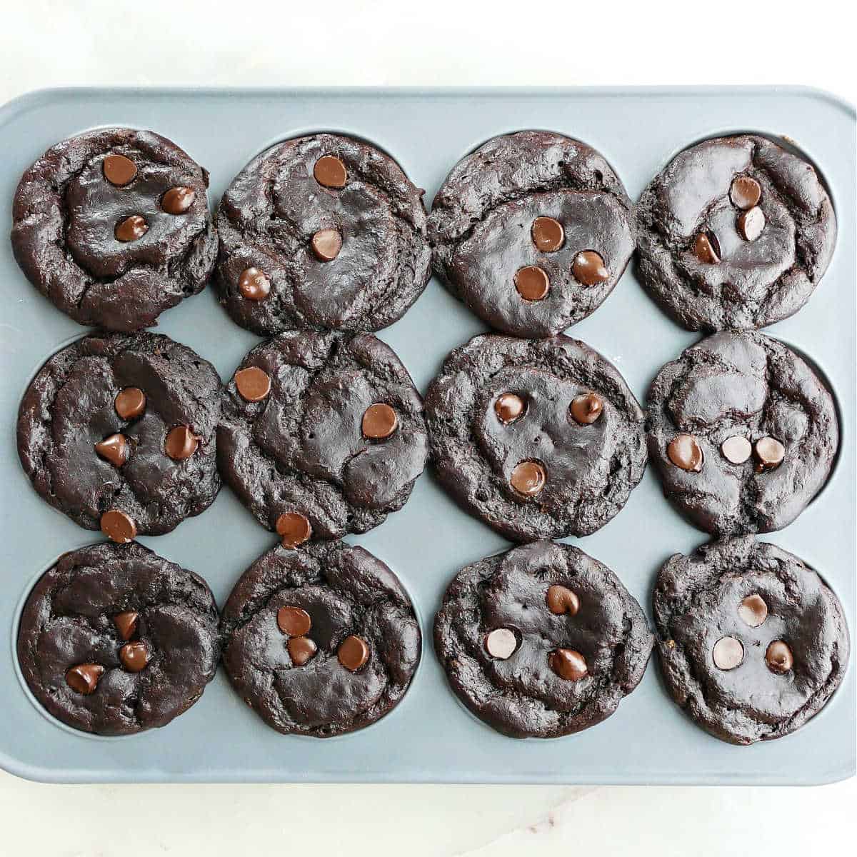 Silicone muffin tray with baked spinach chocolate muffins with chocolate chips.