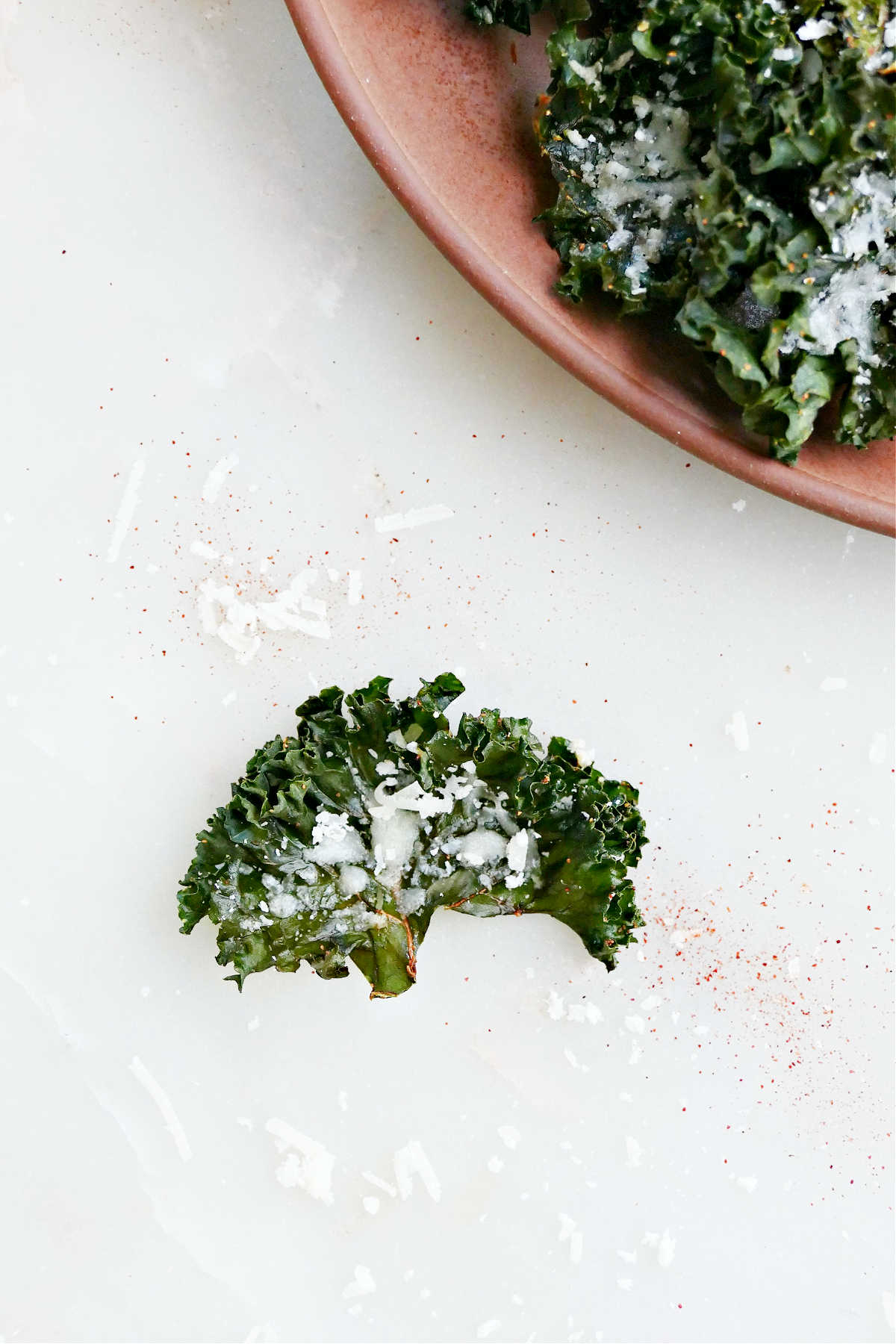 A kale chip with parmesan cheese and seasonings on a counter.