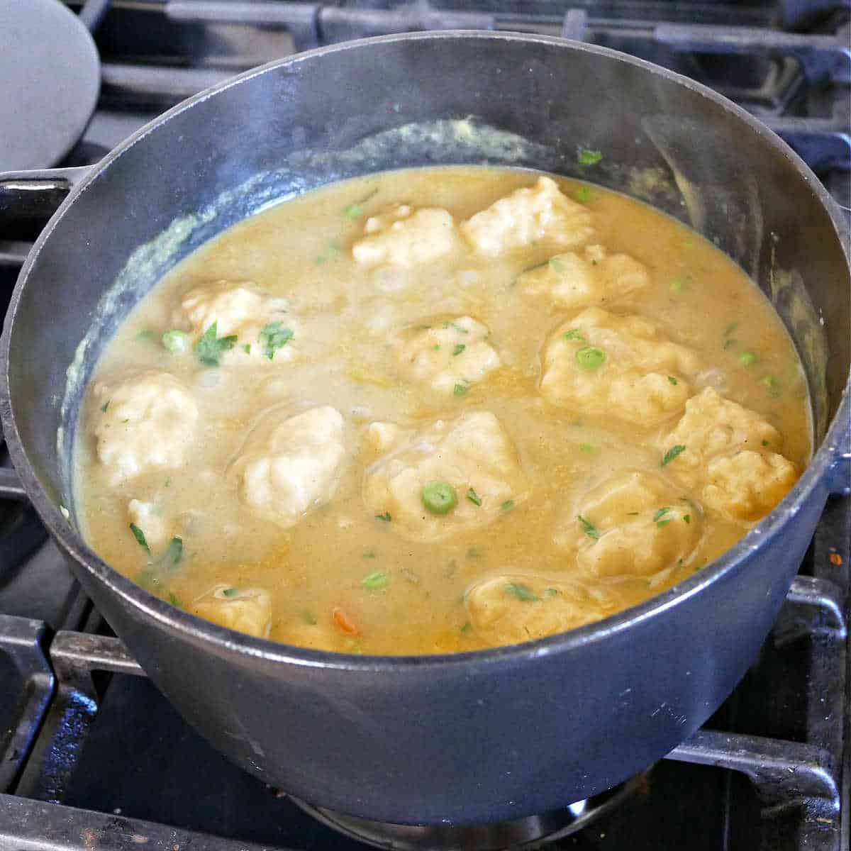 Vegan chicken and dumpling soup with cooked dumplings in a soup pot.