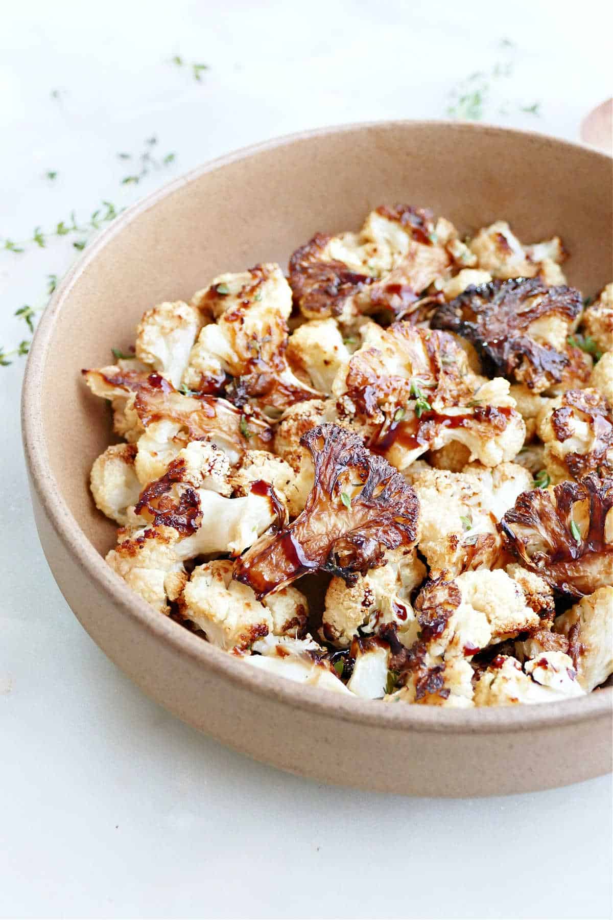 Roasted balsamic cauliflower florets in a brown serving dish.