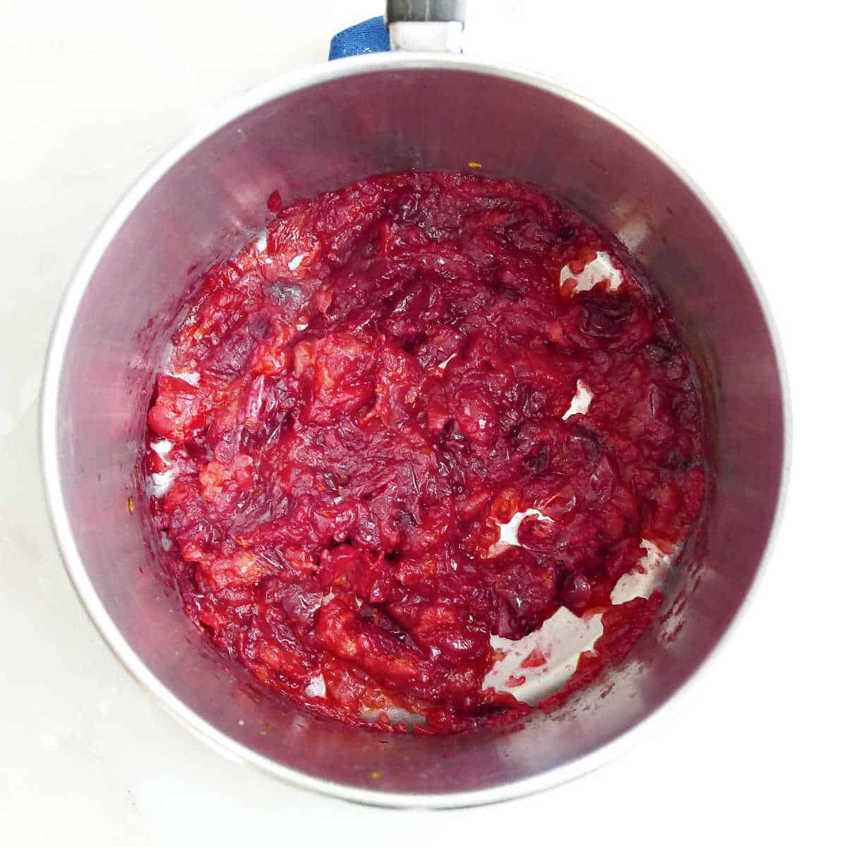 Cranberry sauce cooked with orange juice and zest in a saucepan.