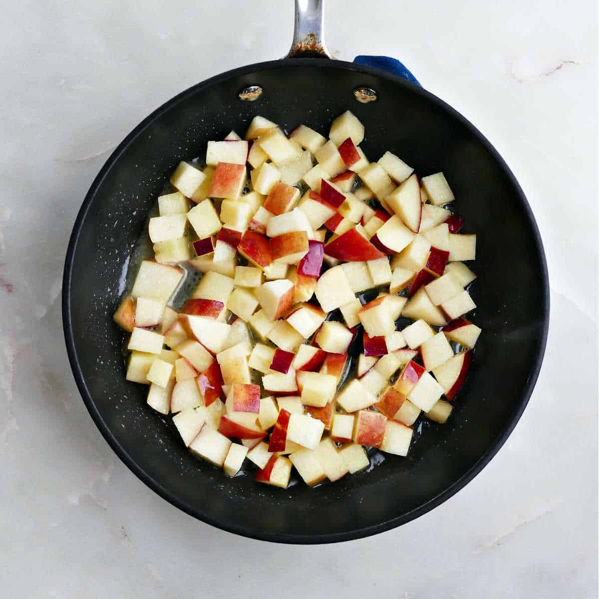 Diced apples in a skillet before being cooked.