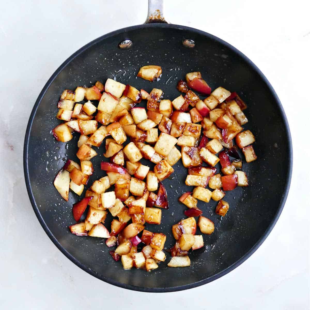 Caramelized diced apples in a skillet after being cooked.