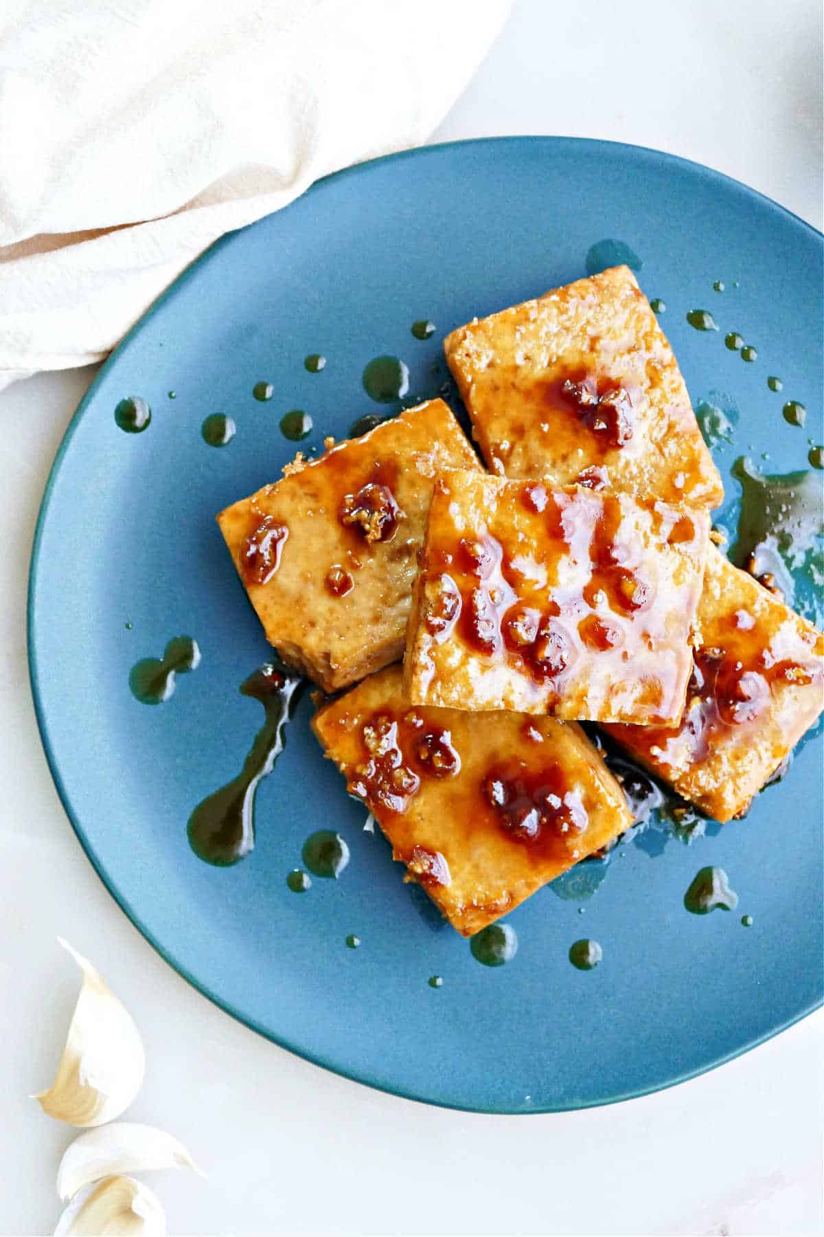 Maple glazed tofu in squares stacked on top of each other on a blue plate.