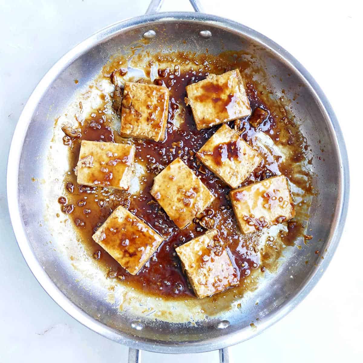 Cooking tofu in a maple glaze in a skillet.