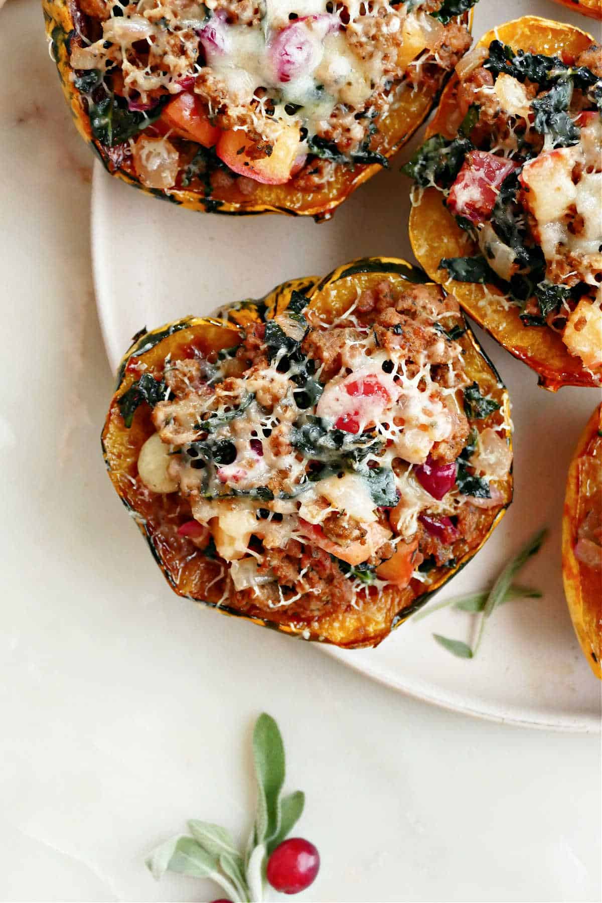 Carnival squash after being baked and stuffed with filling and cheese on a plate.