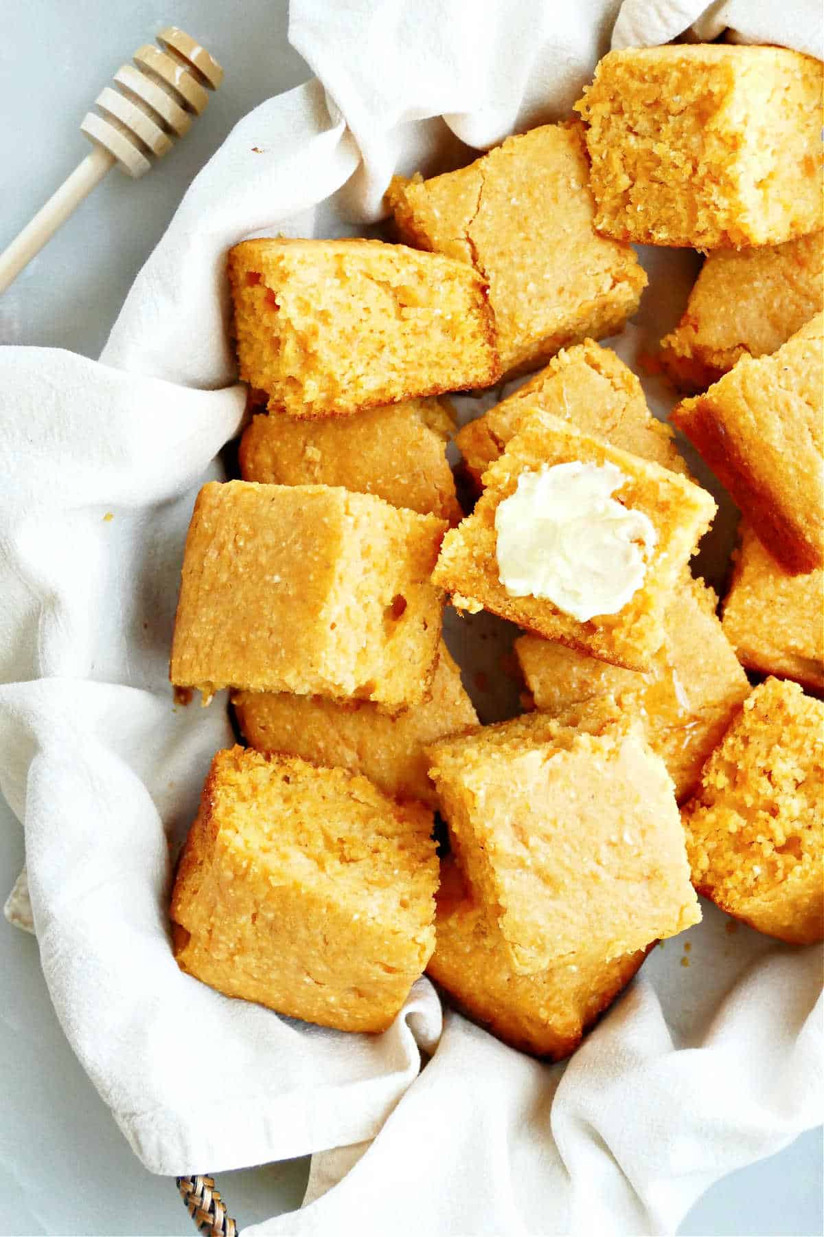 Easy homemade sweet potato cornbread in a basket with one square topped with butter.