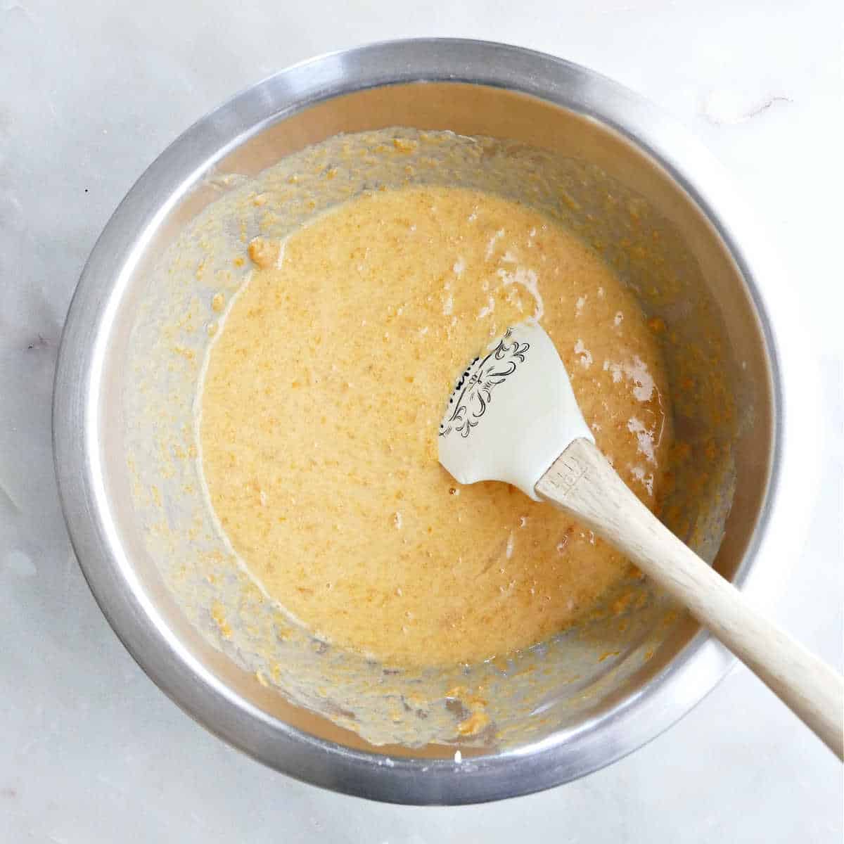 Mixing the sweet potato puree in a large stainless mixing bowl.