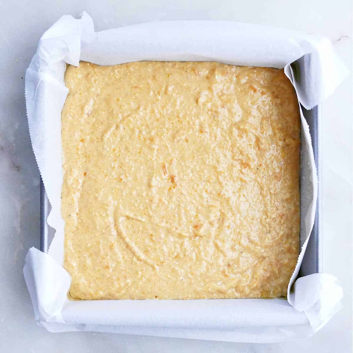 Sweet potato cornbread batter in a parchment lined baking pan.