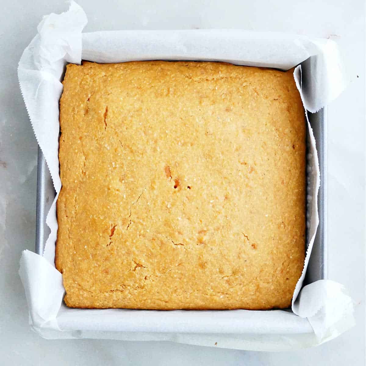 Homemade sweet potato cornbread in a parchment lined pan after baking.