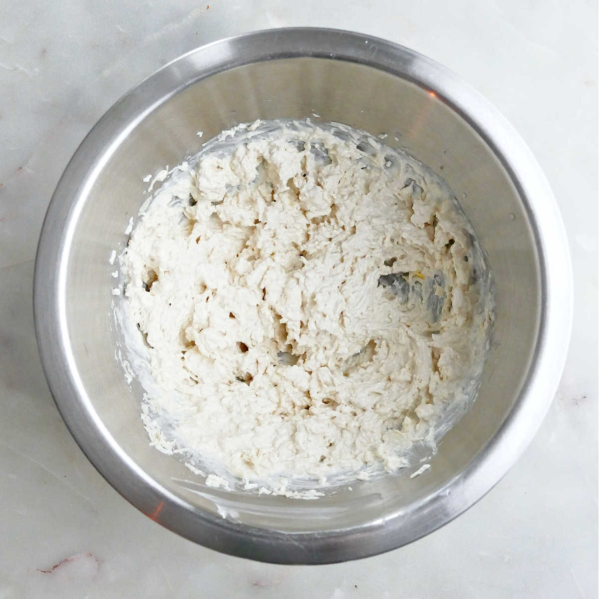 Cream cheese, mozzarella, parmesan, and seasonings mixed together in a bowl.