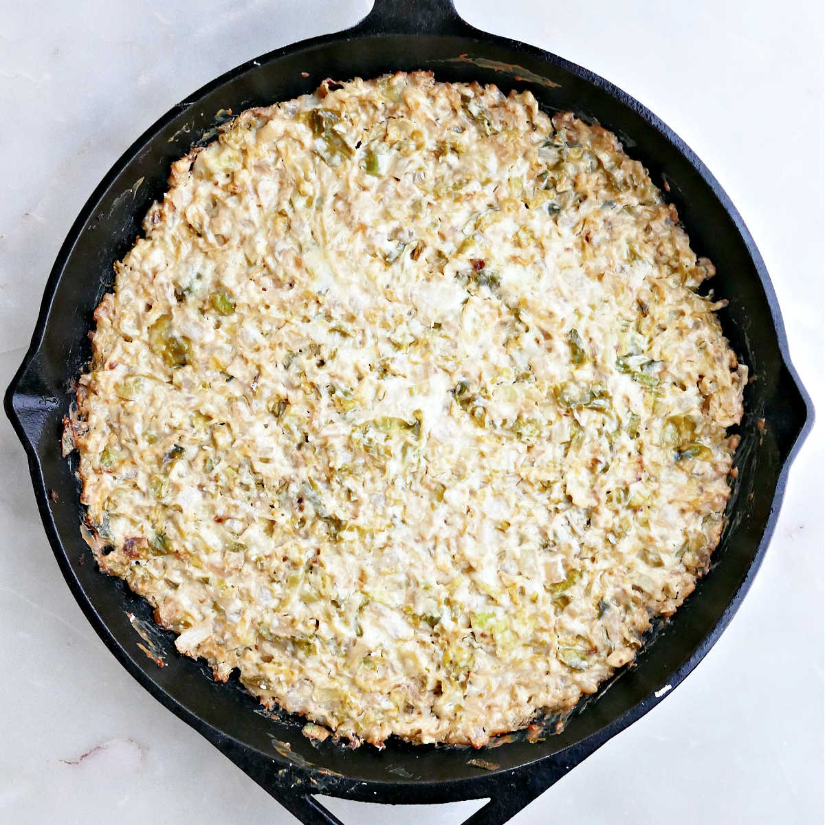 Hot veggie and cheese dip in a cast iron skillet after coming out of the oven.