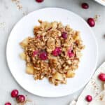 A scoop of apple cranberry baked oatmeal on a white plate.