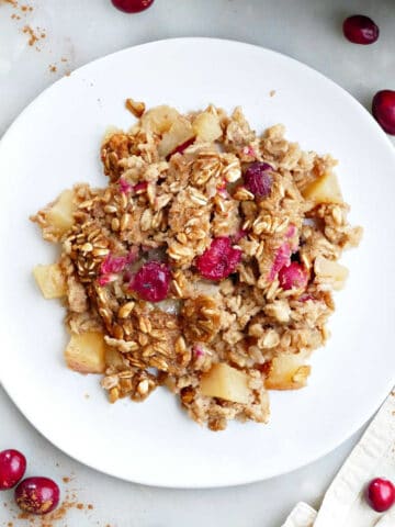 A scoop of apple cranberry baked oatmeal on a white plate.