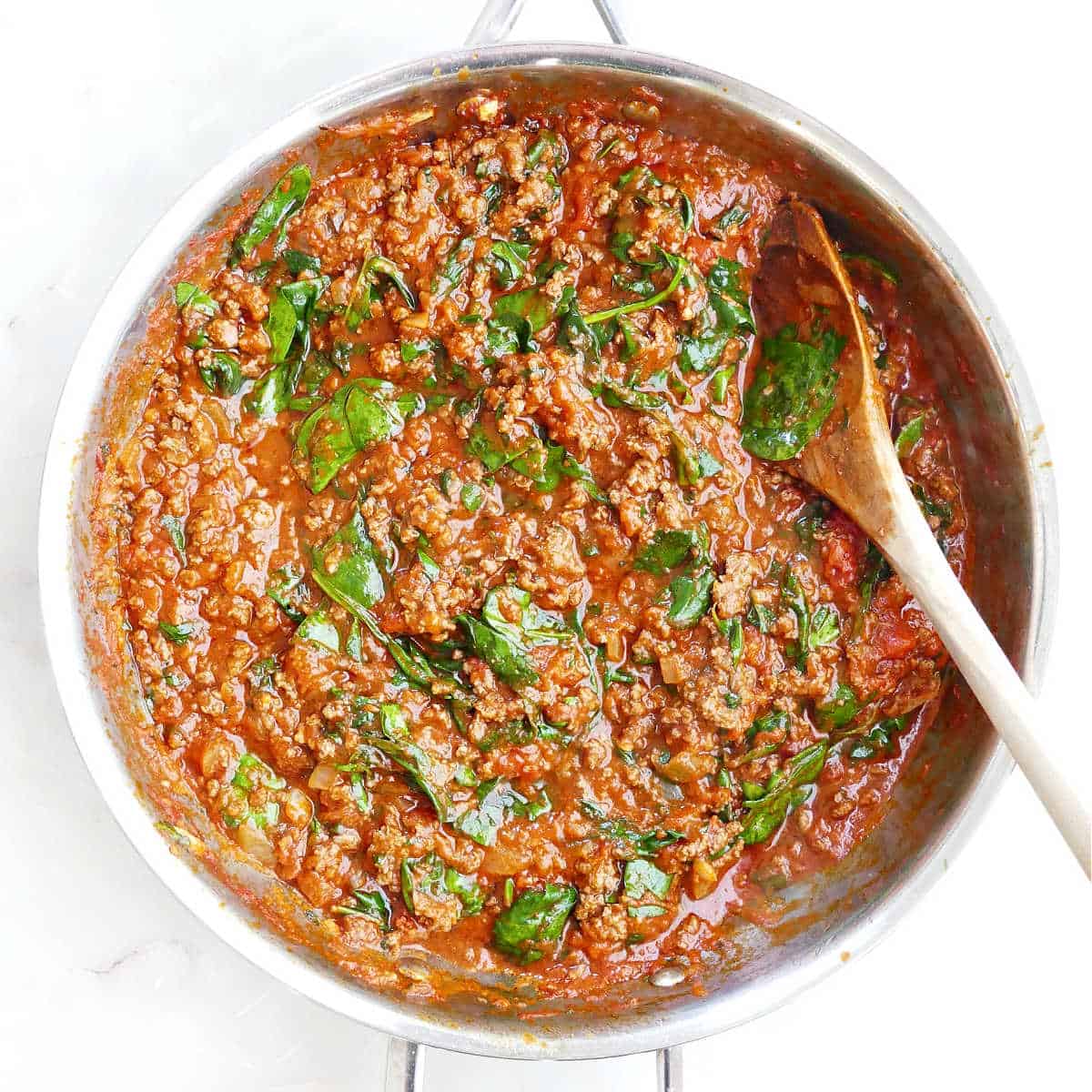 Lasagna beef filling with spinach and tomato sauce in a skillet.