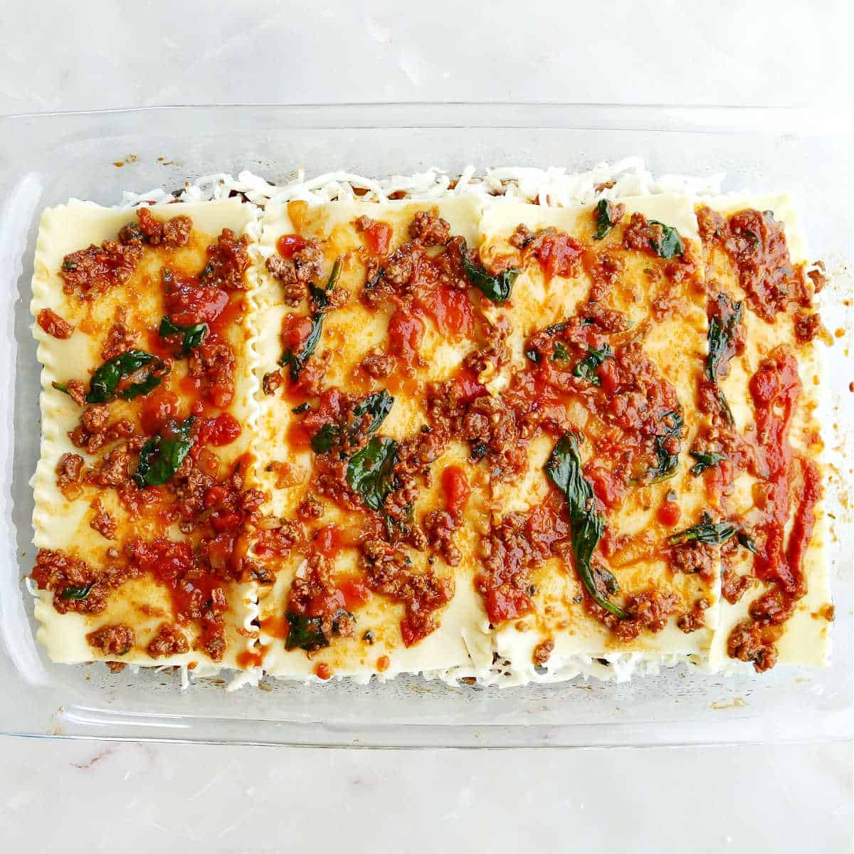 Lasagna prepared for baking in a tray.