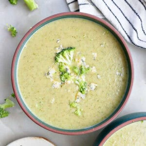 Broccoli and blue cheese soup in a bowl next to toppings and a napkin.