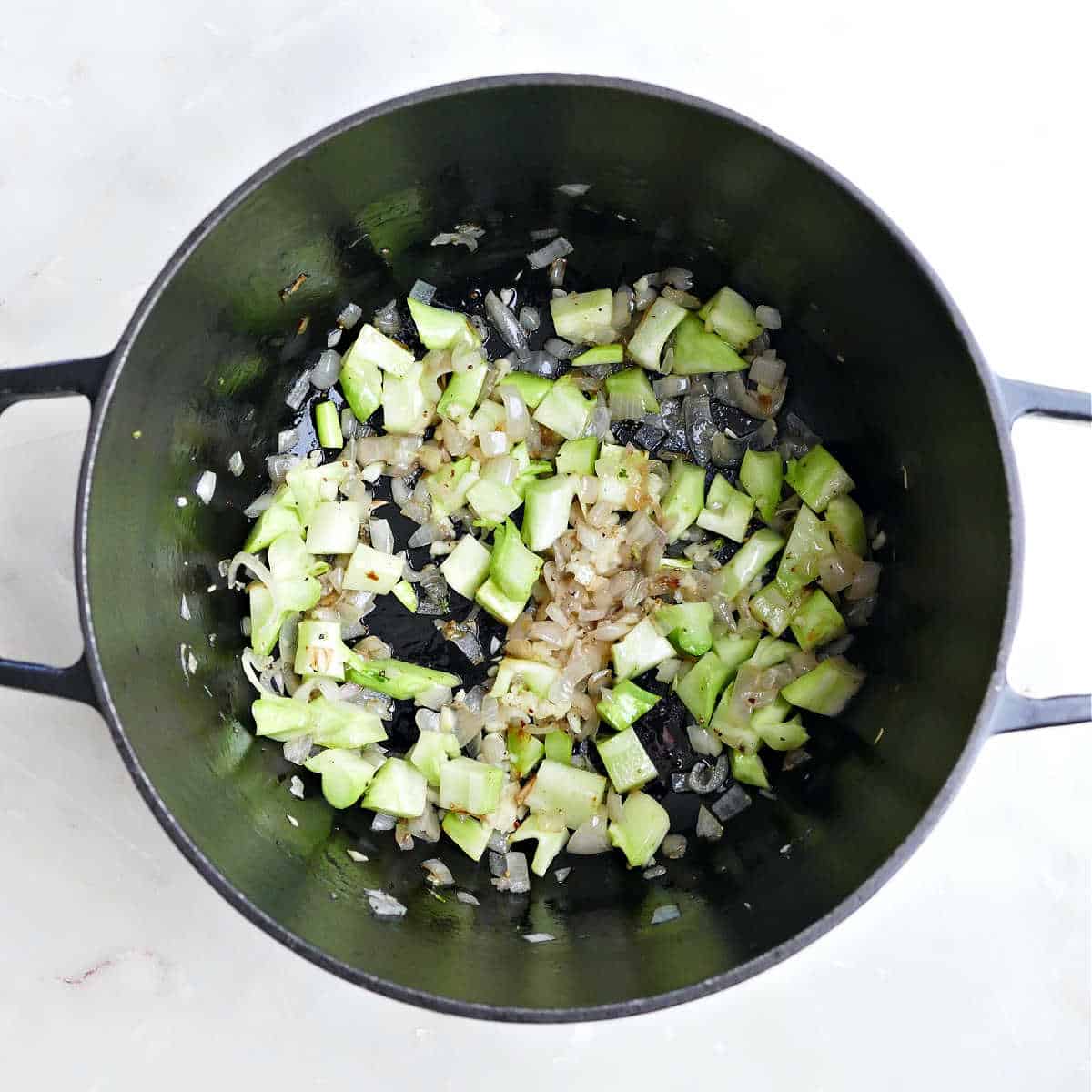 Shallots, garlic, and broccoli stalks cooking in a Dutch oven.