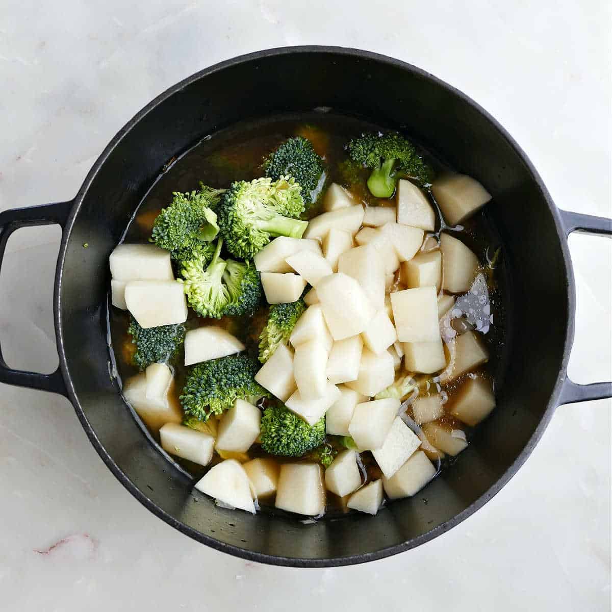 Vegetable ingredients for broccoli blue cheese soup cooking in a Dutch oven.