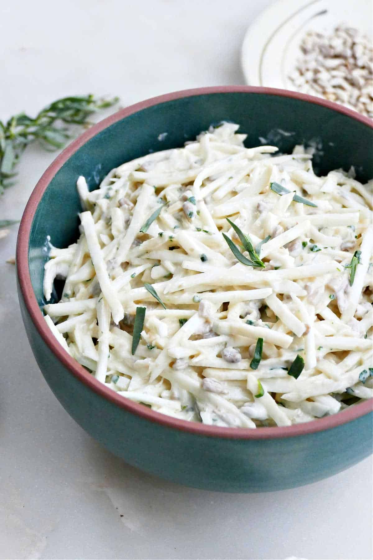 Grated celeriac slaw with yogurt dressing and tarragon in a bowl.